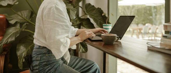 a woman sitting at a table using a laptop computer_edited